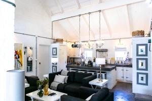 a living room with black furniture and a kitchen at The Bay Cottage in Pringle Bay