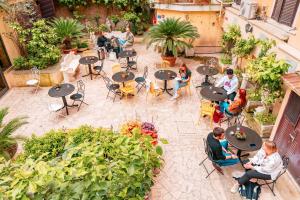 a group of people sitting at tables in a garden at Ostello Bello Roma Colosseo in Rome