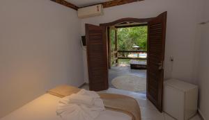 a bedroom with a bed and an open door at Casa La Luna - Arraial D'Ajuda in Arraial d'Ajuda