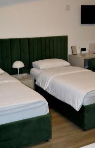 two beds in a room with a green headboard at Mas Motel in Bosanska Gradiška
