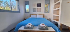 a bedroom with a blue bed with two towels at Nof Beresheet suites in Neot Golan