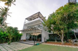a large white house with a tree in front of it at Charlie in Ambalangoda