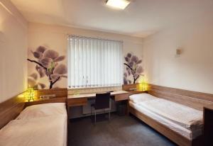 a room with two beds and a desk and a window at GREEN HOTEL Ostrava in Jáma František