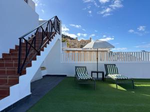 a patio with two chairs and an umbrella and stairs at Panoramic View Balcón del Atlántico in Adeje
