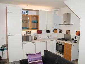 a kitchen with white cabinets and a black couch at Home Sweet Home in Lavagna