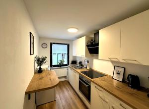 a kitchen with white cabinets and a wooden counter top at ODA Living Lüneburg in Lüneburg