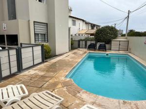 a swimming pool with lounge chairs and a house at Bahia creek in Las Grutas
