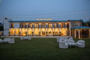 a hotel with white chairs and a building at Hulara Meadows in Lucknow