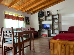 a dining room with a table and chairs and a tv at Casita Los Samoyedos in Lago Puelo