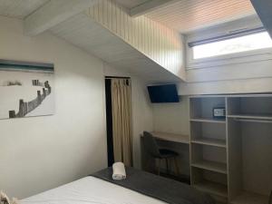 a bedroom with a bed and a desk and a window at Hotel Cote et Lac in Biscarrosse