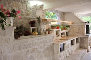 科尔丘拉格吉奇公寓酒店的石制厨房,在架子上设有水槽和鲜花