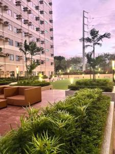 a large building with a park with bushes and furniture at Sweetluxx - SMDC Green 2 Residences Staycation in Dasmariñas
