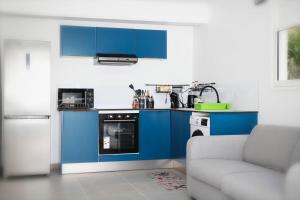 a kitchen with blue cabinets and a couch at Appartement Ti Colibri in Rivière-Salée +30 photos