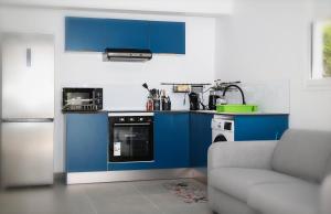 a kitchen with blue cabinets and a couch at Appartement Ti Colibri in Rivière-Salée