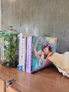 three books sitting on a shelf next to a jar at Balay Yuhom in General Luna