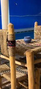 a wooden table with wicker chairs and a bowl on it at Hotel Appart HB in Marrakesh