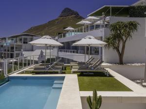 a hotel with a swimming pool with chairs and umbrellas at South Beach Camps Bay Boutique Hotel in Cape Town