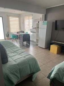 a bedroom with a bed and a kitchen with a refrigerator at dpto lofalu in Gobernador Gregores