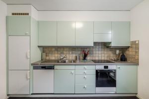 a white kitchen with white cabinets and a sink at WG Zimmer Seilerstrasse in Arbon +10 photos