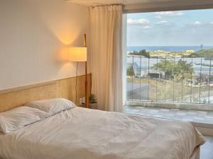 a bedroom with a bed and a large window at Jeju Byeolkkum Pension in Jeju