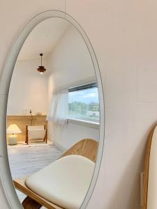 a mirror in a room with a chair and a window at Jeju Byeolkkum Pension in Jeju