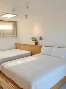 a bedroom with two beds and a window at Jeju Byeolkkum Pension in Jeju +19 photos