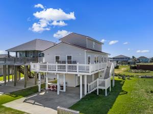 a large white house with a porch and a deck at Once Upon A Tide in Bolivar Peninsula