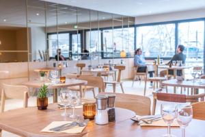 a restaurant with tables and chairs and people in the background at Bhoma Budget Troyes aéroport in Troyes