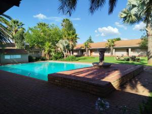 a swimming pool with a fountain in front of a house at Ingwe Guest lodge in Vanderbijlpark