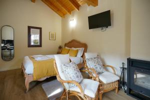a bedroom with a bed and two chairs and a television at Casas da Assureira in Castro Laboreiro