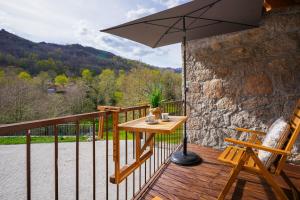 a wooden deck with a table and an umbrella at Casas da Assureira in Castro Laboreiro