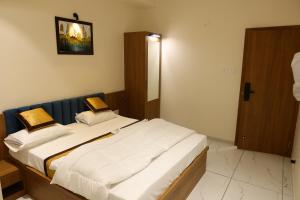 a bedroom with two beds with white sheets at Rajwadi Hotel Inn in Valsād
