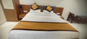 a bedroom with a large bed with white and brown sheets at Rajwadi Hotel Inn in Valsād