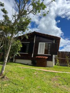 a brown house with a tree in front of it at Chalé Flor da Fortuna in Lavras Novas