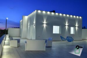 a patio with chairs and a white building at night at Hotiday Room Collection - Torre Lapillo in Torre Lapillo