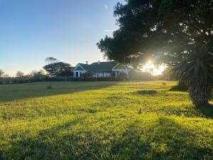 a house in the middle of a field with the sun setting at Kingston Farm in Bathurst