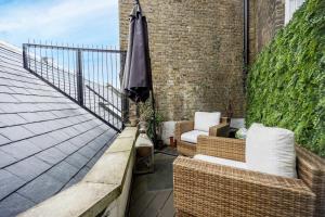 a patio with two chairs and an umbrella on a balcony at Buckingham & Lloyds Knightsbridge in London