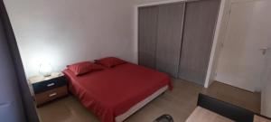 a small bedroom with a red bed and a night stand at Les chambres du Manguier in Mamoudzou