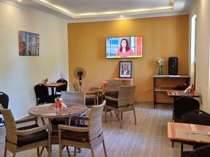 a restaurant with tables and chairs and a tv on the wall at Lorateng' Resort - Rusinga in Mbita