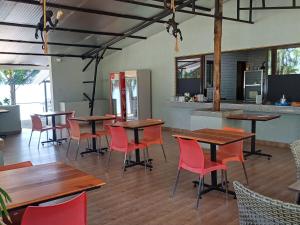 a restaurant with wooden tables and red chairs at Lorateng' Resort - Rusinga in Mbita