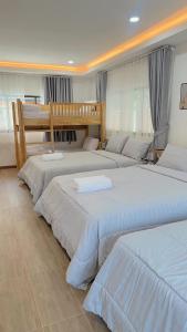 a group of three beds in a room at Chaisona at Khanom Storey in Ban Phaeng