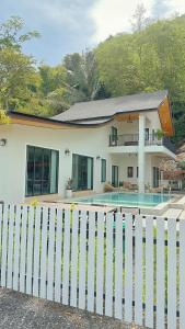 a white fence in front of a house with a pool at Chaisona at Khanom Storey in Ban Phaeng