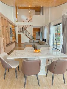 a living room with a large white table and chairs at Chaisona at Khanom Storey in Ban Phaeng