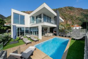 a villa with a swimming pool and a house at OurMadeira - BeachFront in Madalena do Mar