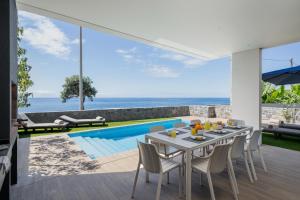 a dining room with a table and chairs and a pool at OurMadeira - BeachFront in Madalena do Mar