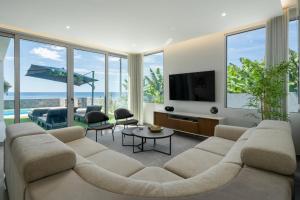 a living room with a couch and a tv at OurMadeira - BeachFront in Madalena do Mar