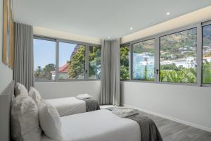 two beds in a room with large windows at OurMadeira - BeachFront in Madalena do Mar +34 photos