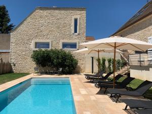 a pool with chairs and umbrellas next to a building at L'Annexe Deveney-Mars in Puligny-Montrachet