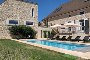 a swimming pool with chairs and umbrellas next to a building at L'Annexe Deveney-Mars in Puligny-Montrachet