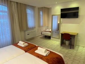 a hotel room with two beds and a desk at Pombal City House in Pombal